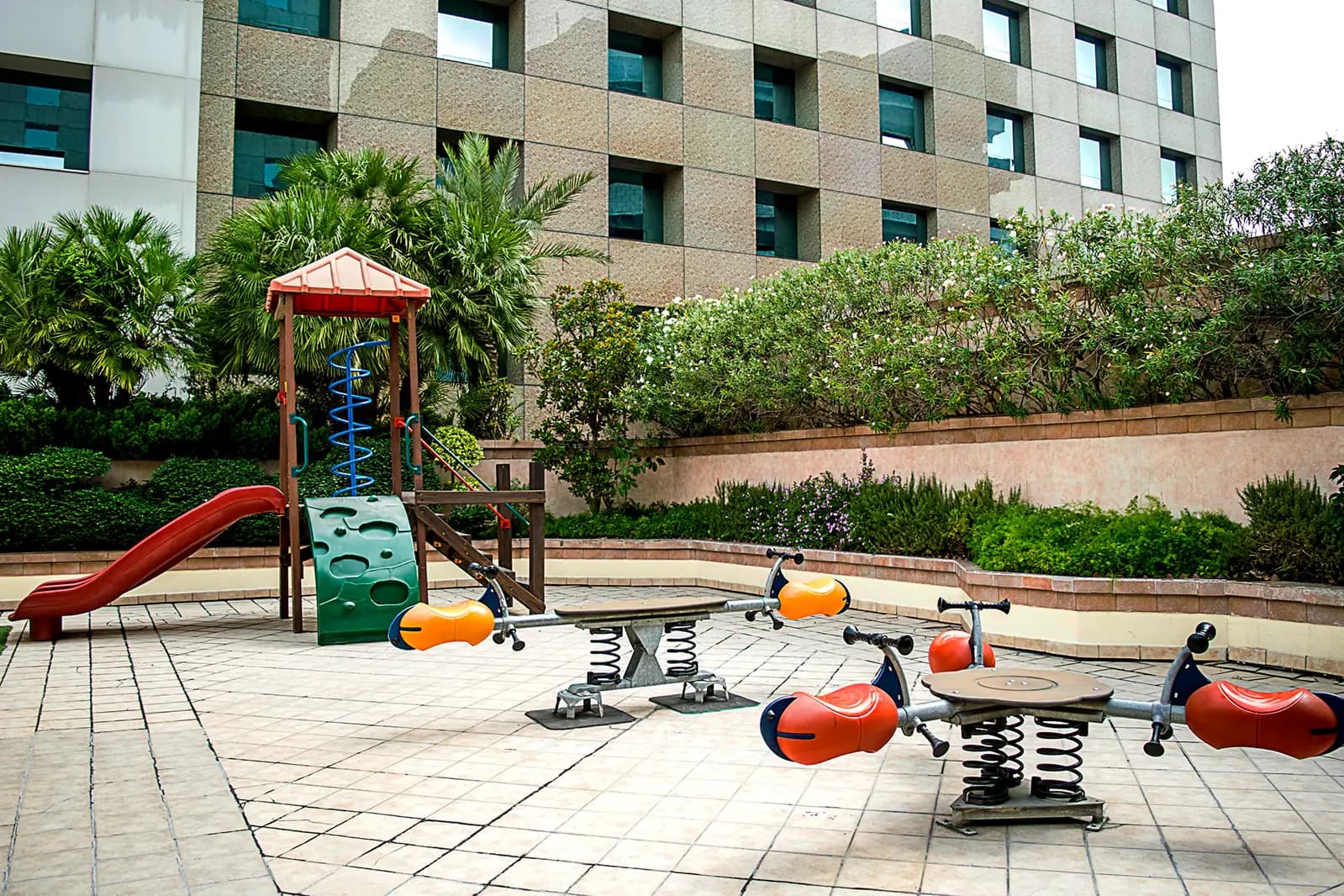 Área de juegos infantiles con resbaladilla y jardines